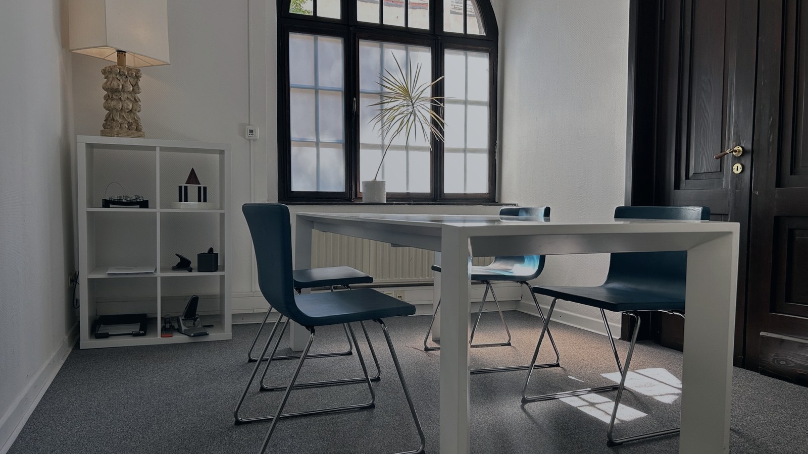 Besprechungsraum der Kanzlei mit Tisch, Stühlen und Rundbogenfenster