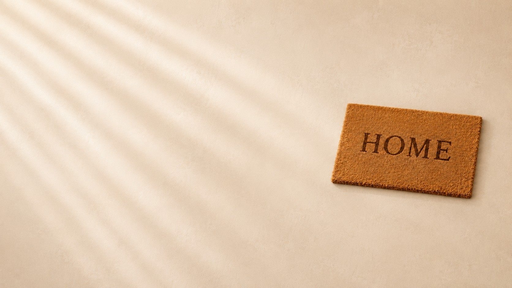 Fußmatte mit dem Schriftzug Home auf hellem Boden als Symbol für Ankommen, Kontakt und persönliche Beratung
